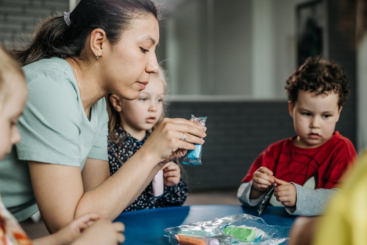 Preschool children enjoy a hands-on artistic activity with their teacher indoors.